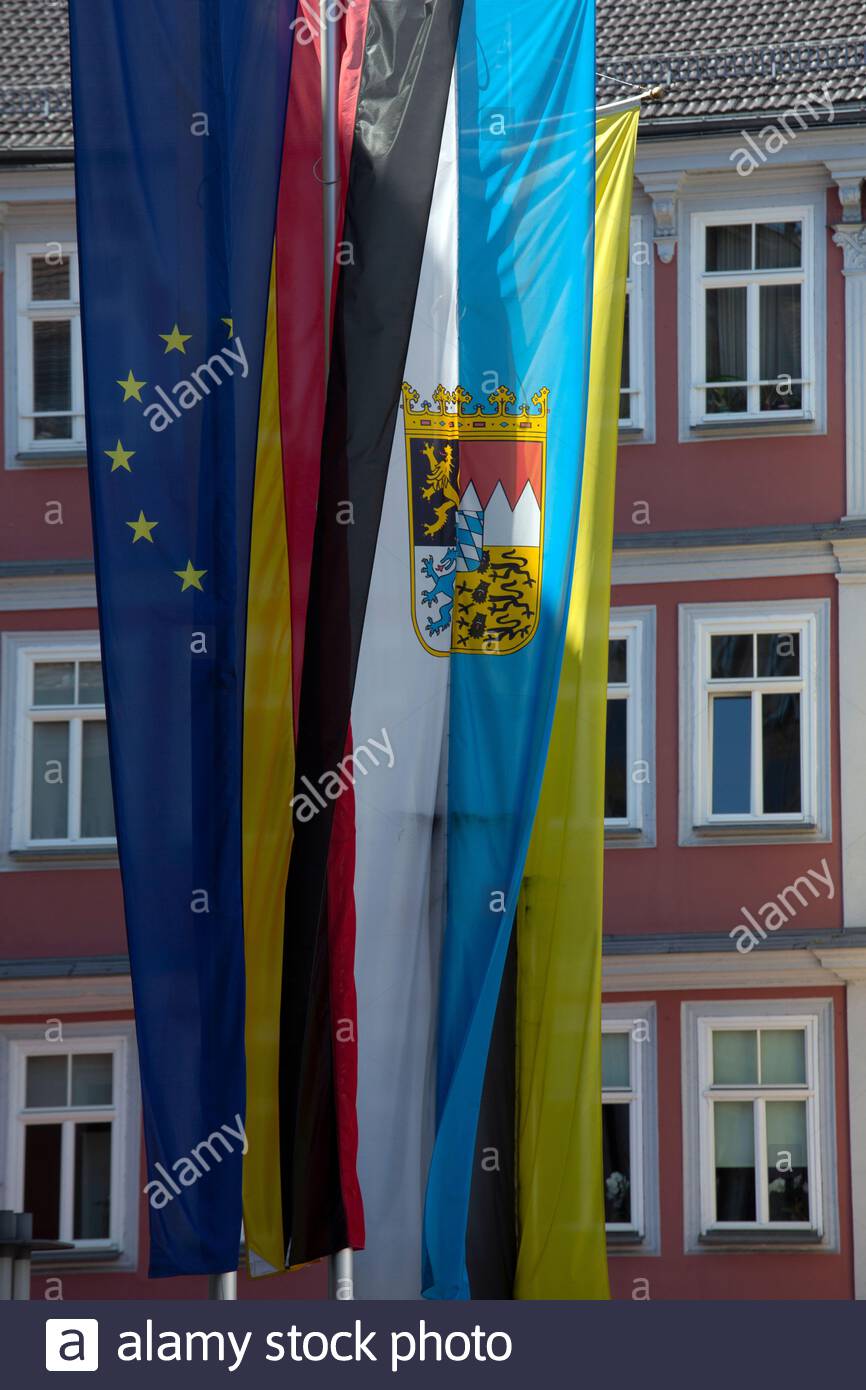 Four flags hanging in sunshine on the town hall of Coburg in Bavaria, the EU flag, the German flag as well as the Bavarian and Coburg flags. Stock Photo