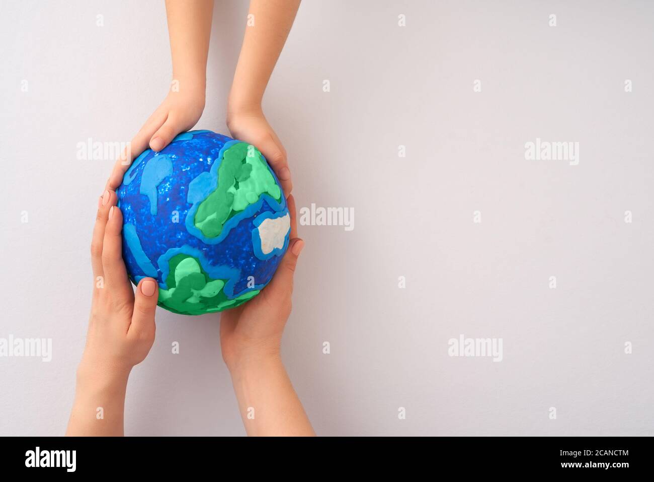 Child and adult holding planet in hands against white background. Earth ...