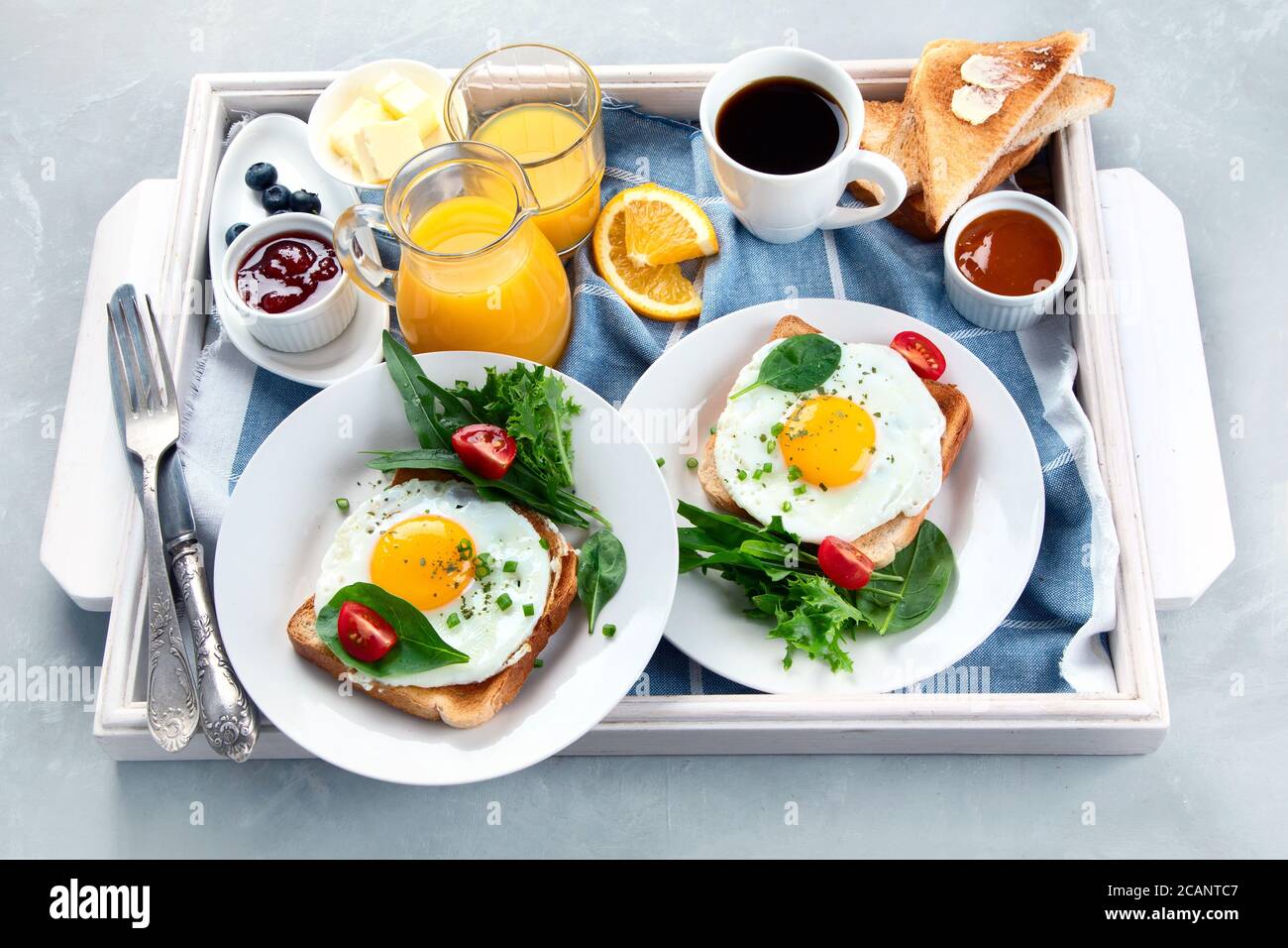 Traditional American breakfast served in white wooden tray on grey background . Stock Photo