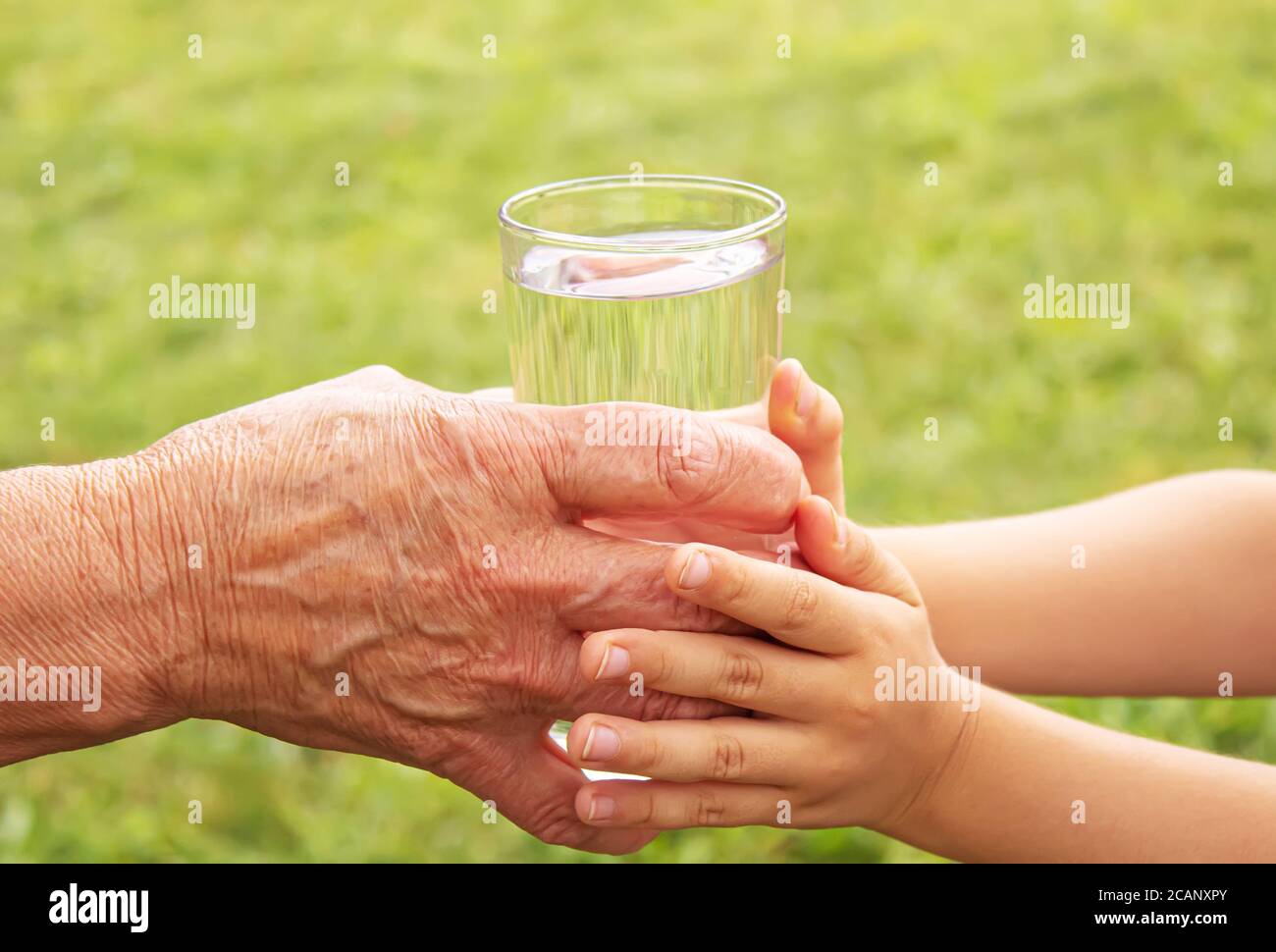 Grandmother giving a glass of clean water to a child. Selective focus. Stock Photo