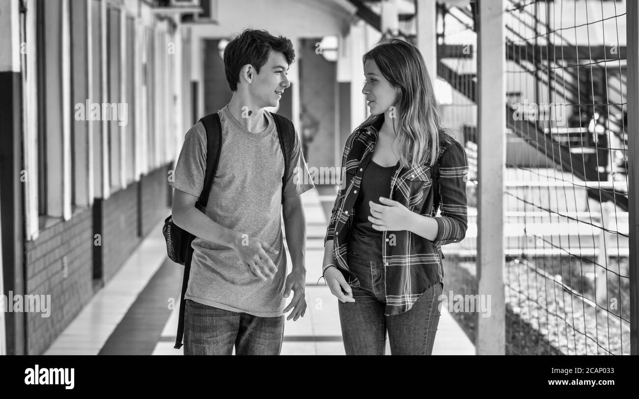Two caucasian teenagers friends happy returning to school speaking along the hallway. Back to school concept. Stock Photo