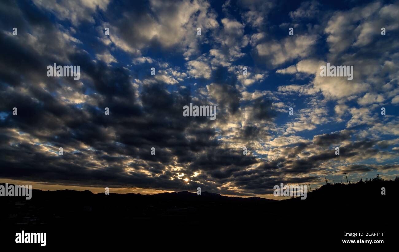 Beams of sunlight coming through storm clouds in Larnaca, Cyprus over a small village surrounded by mountains Stock Photo