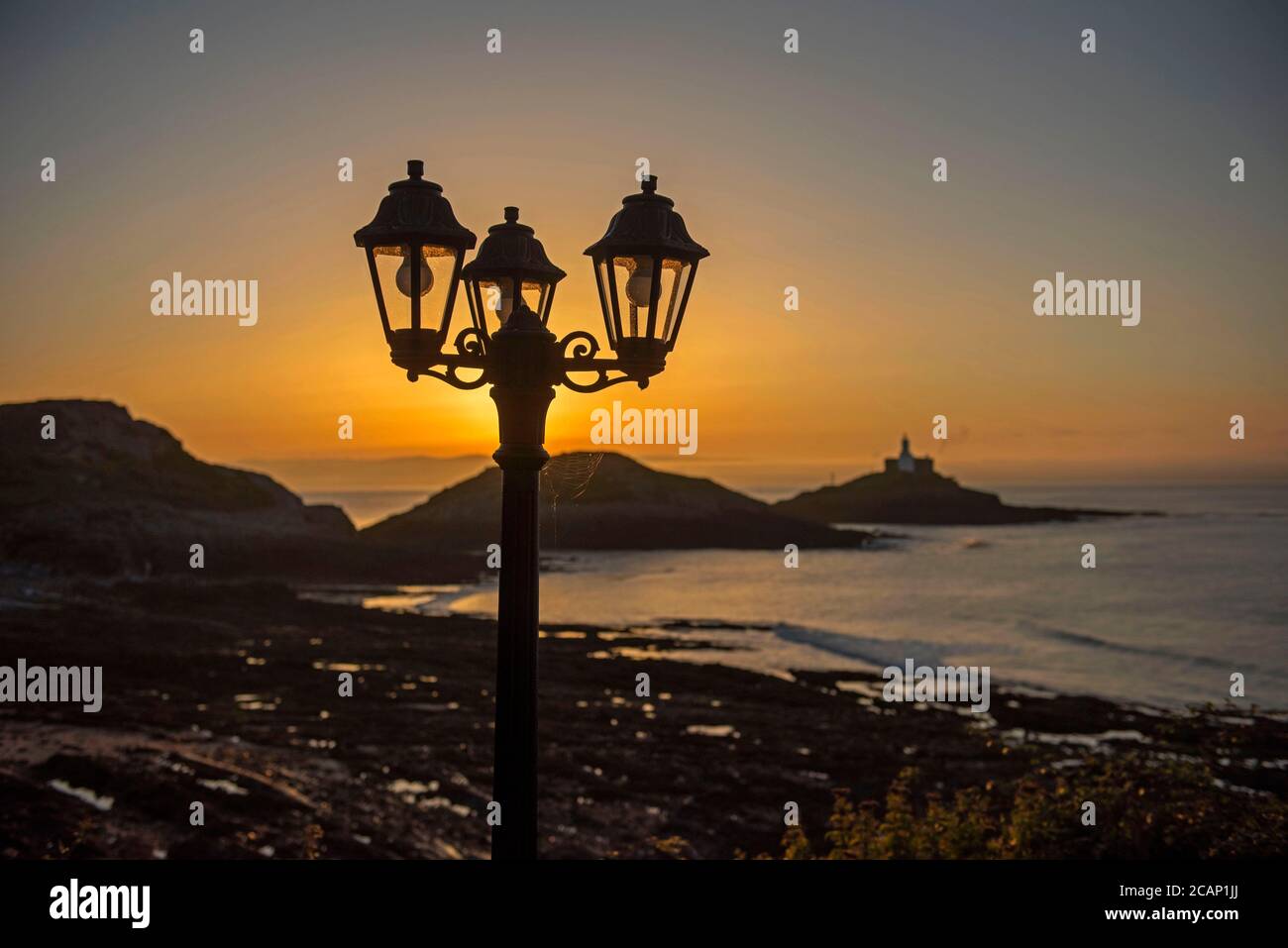 Mumbles, Swansea, UK. 8th Aug, 2020. The sun rises over the Mumbles Lighthouse near Swansea this morning as seen from outside Castellamare Restaurant at the start of a stunning UK summers day. Credit: Phil Rees/Alamy Live News Stock Photo