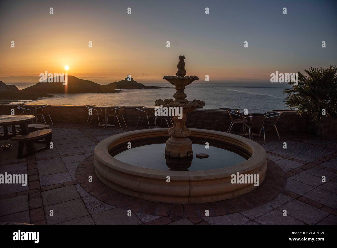 Mumbles, Swansea, UK. 8th Aug, 2020. The sun rises over the Mumbles Lighthouse near Swansea this morning as seen from outside Castellamare Restaurant at the start of a stunning UK summers day. Credit: Phil Rees/Alamy Live News Stock Photo