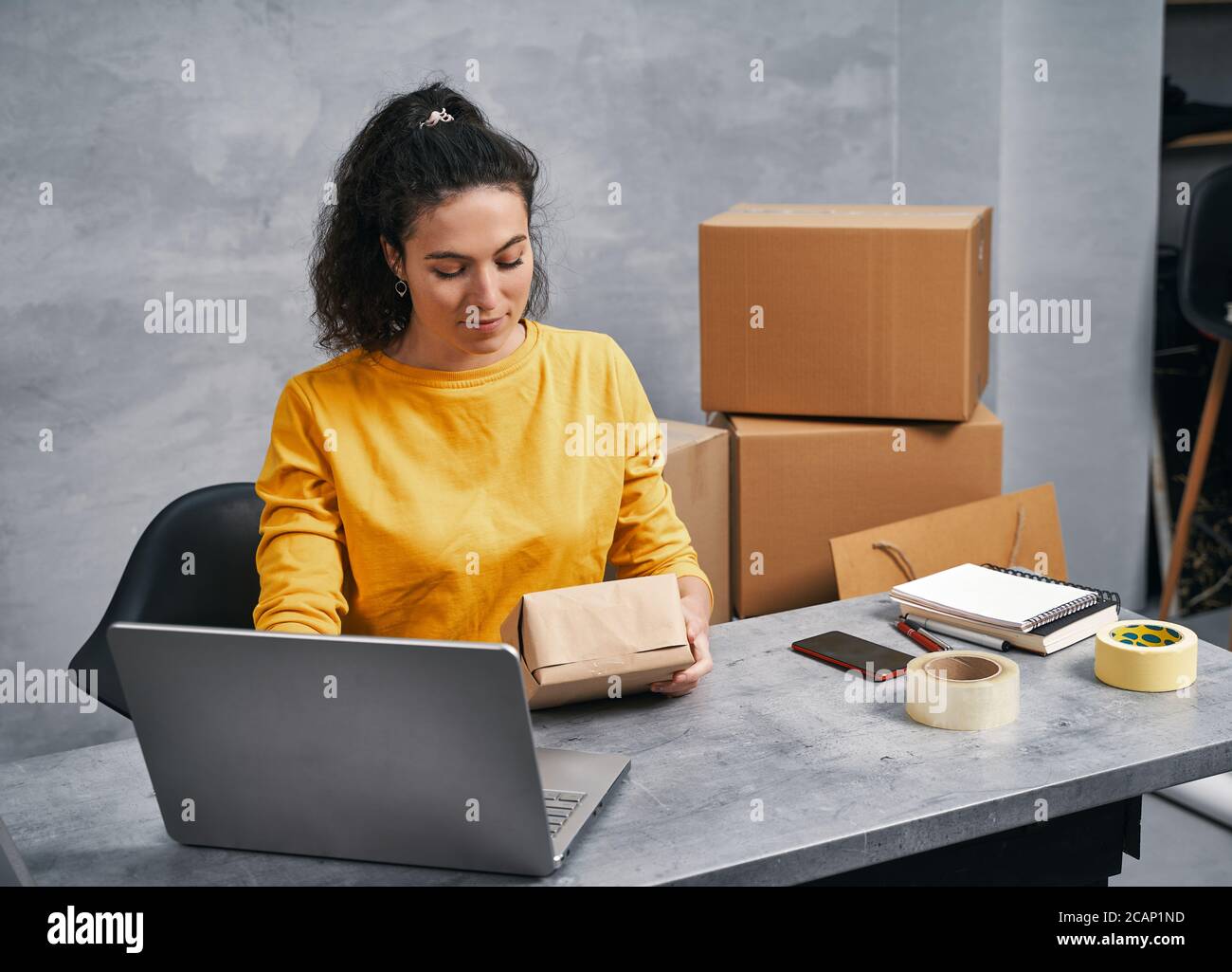 Woman sending parcel using her laptop. Working from home Stock Photo ...
