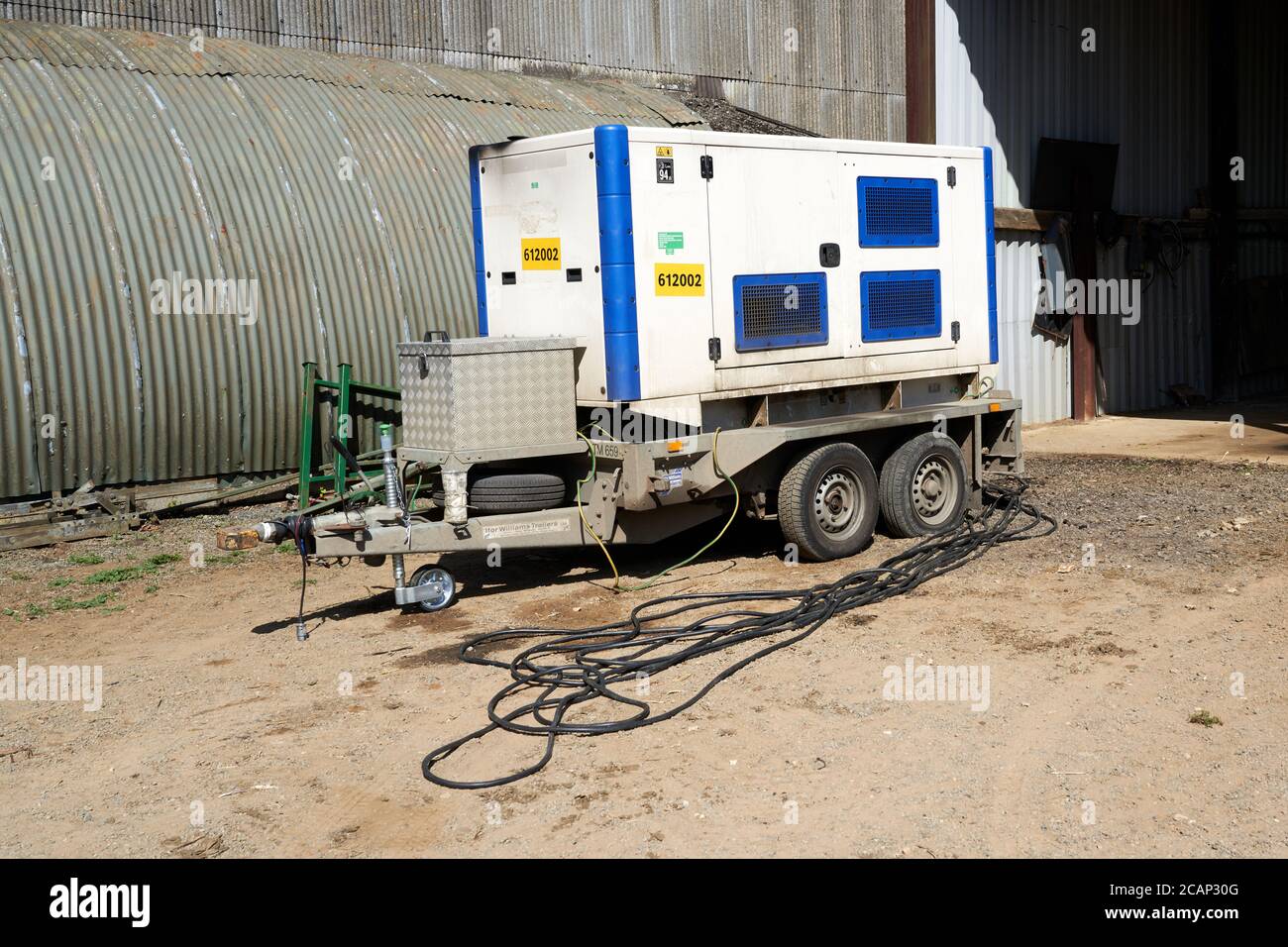 A western power 150 kVa 3 phase generator on site in a farmyard providing back up power as a result of supply interruption due to maintenance work Stock Photo