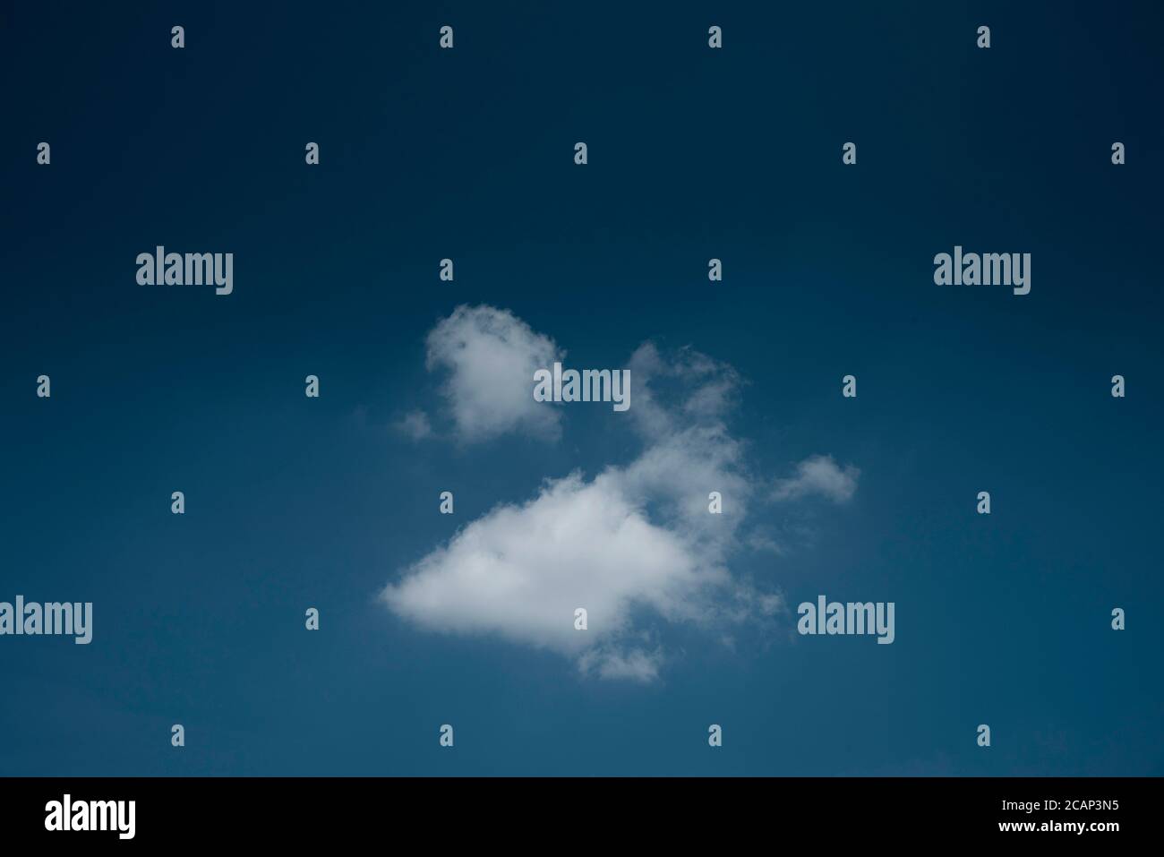 Minimal lonely white cloud in deep blue sky background Stock Photo