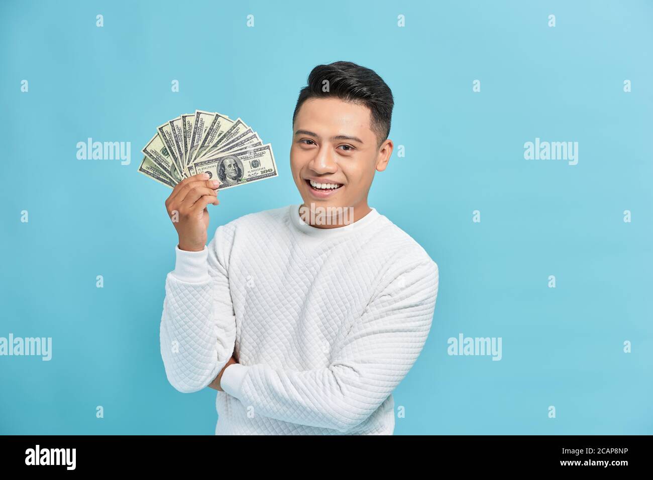 Man holding money and white arrow over blue background Stock Photo