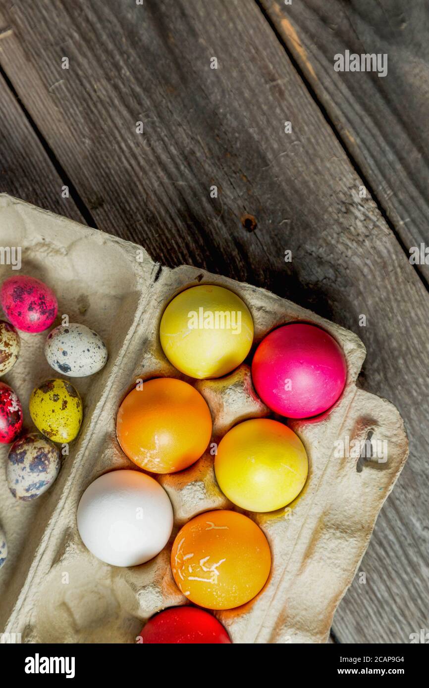 Dyed easter eggs in cardboard box on wooden background. Stock Photo