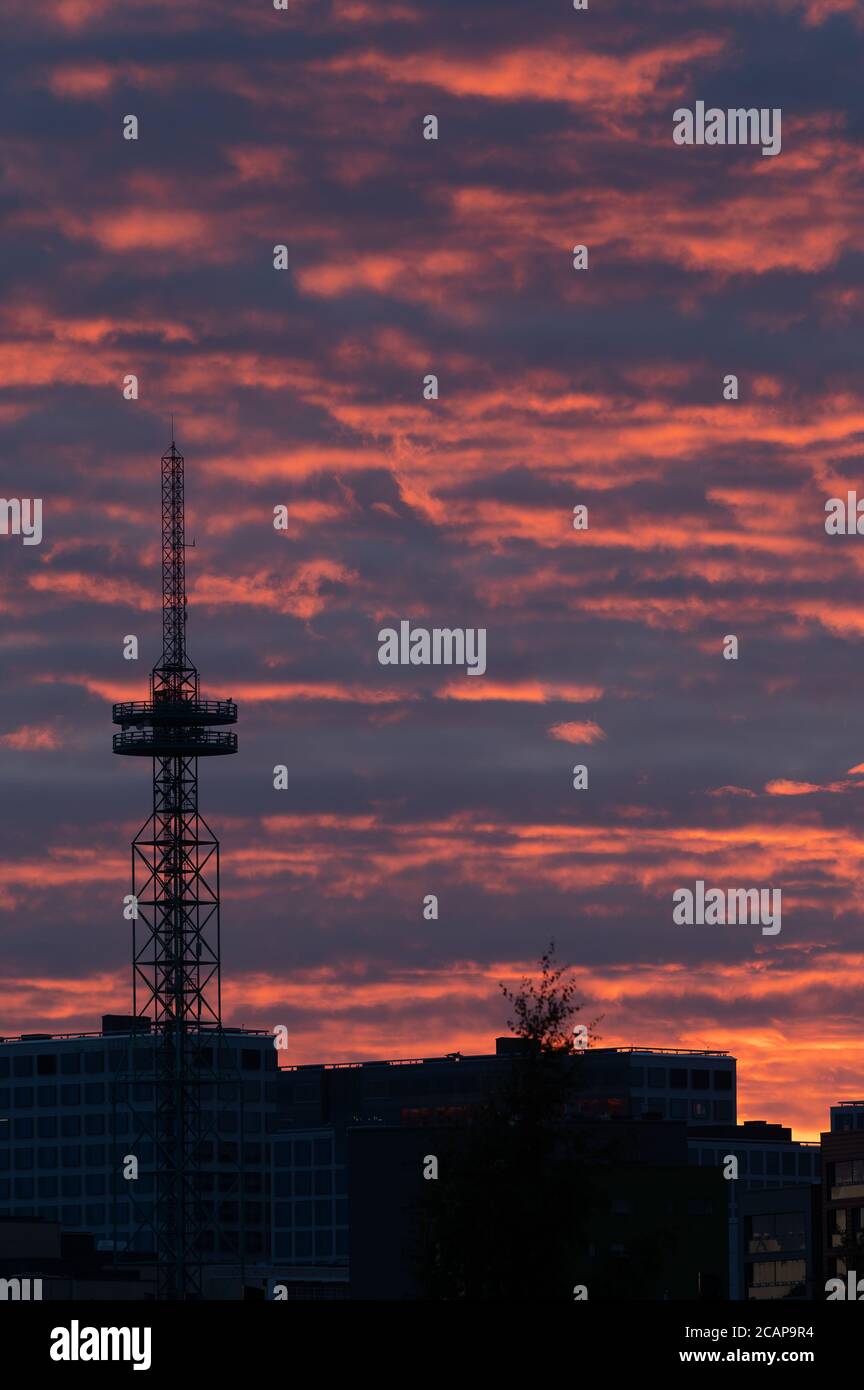 Helsinki / Finland - August 6, 2020: A silhouette of a tall telecommunication / broadcasting tower against vivid red sky on a cloudy summer evening. Stock Photo