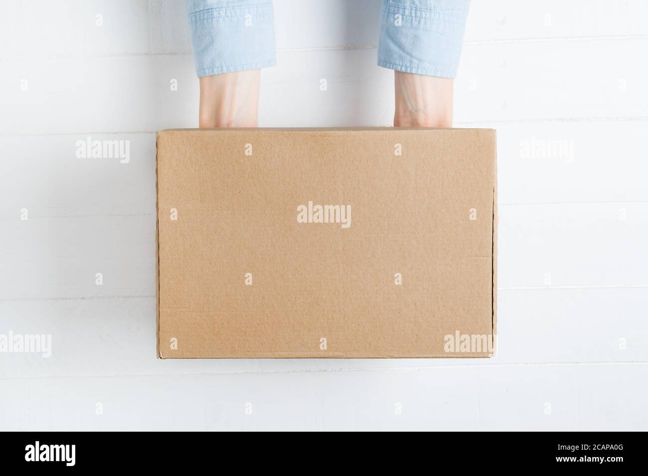 Rectangular cardboard box in female hands. Top view, white background Stock Photo
