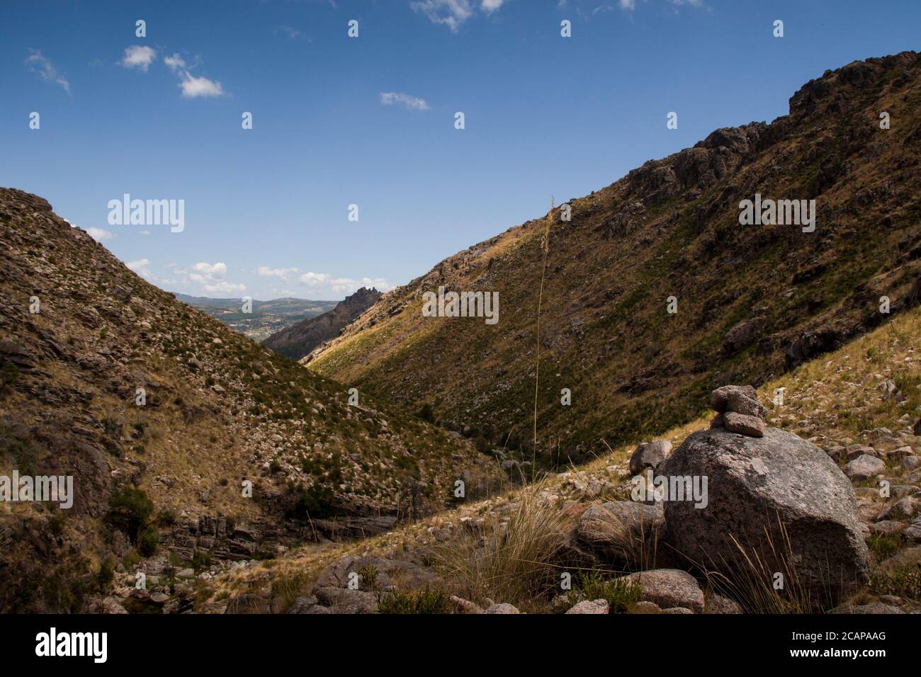 Mountain valley landscape under blue sky and mountain guiding stones on first plane Stock Photo