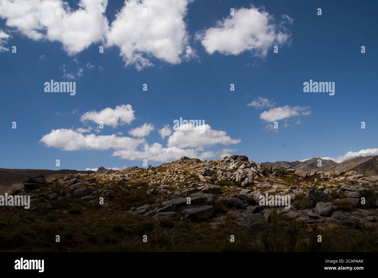 Contrast between light and shadow on rocky mountain terrain under cloudy blue sky Stock Photo