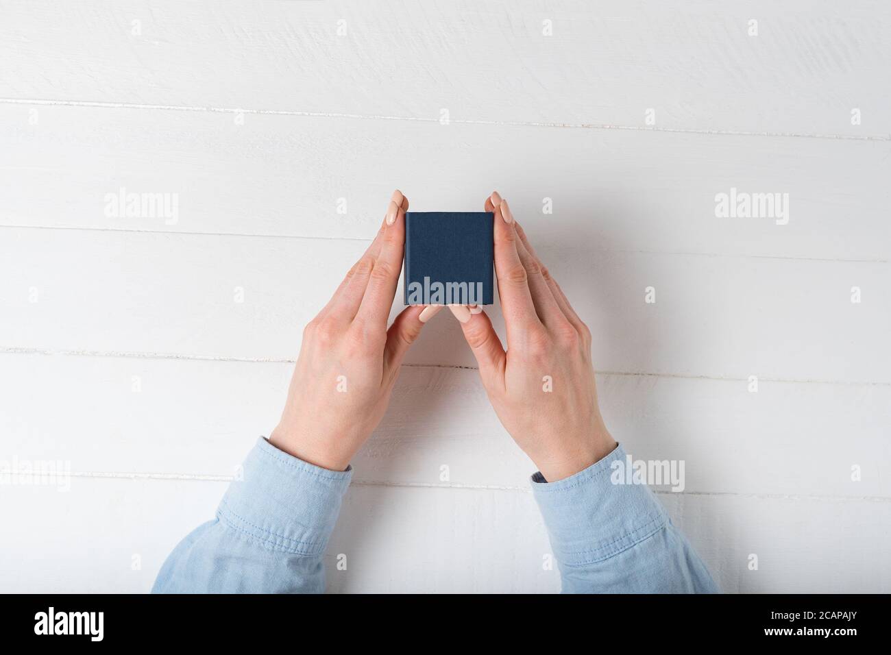Small blue box in female hands. Present. White background Stock Photo