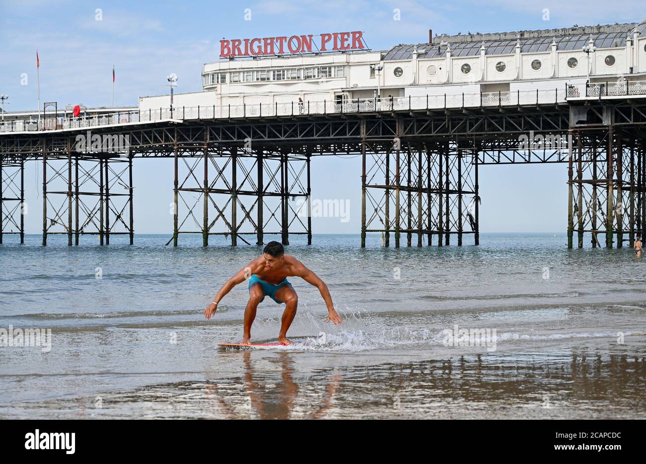 Brighton UK 8th August 2020 - A young man enjoys surfing on the edge of Brighton beach on a hot day as the temperature is forecast to reach over 30 degrees in some parts of the South East : Credit Simon Dack / Alamy Live News Stock Photo