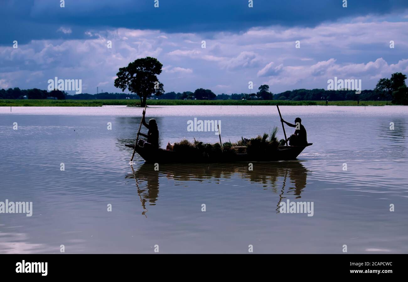 Bangladeshi farmers riding a wooden boat near the riverside Stock Photo