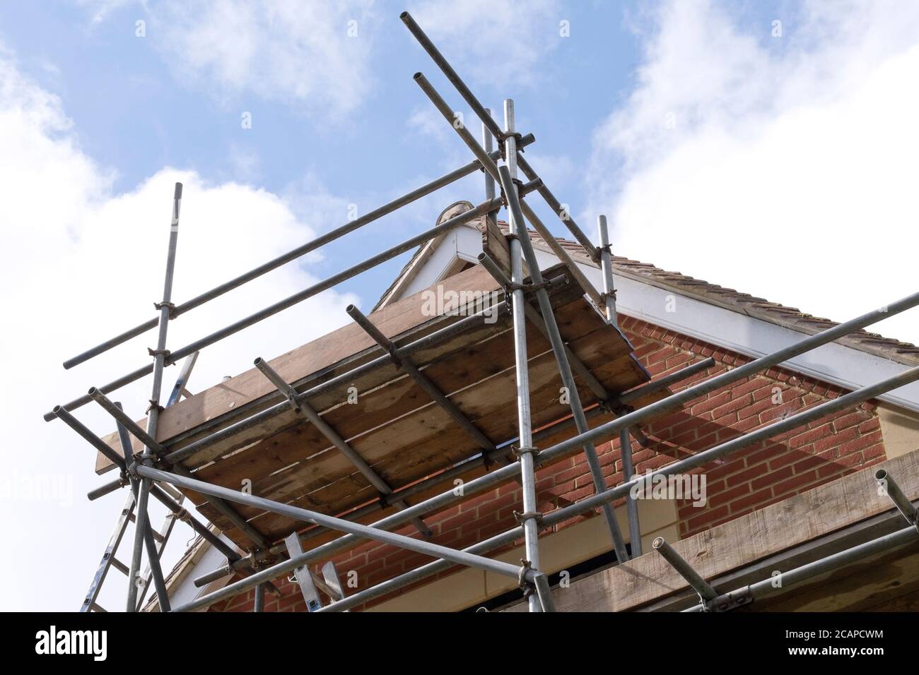 Modern house roof construction with scaffold pole platform. New build domestic building against blue sky with clouds Stock Photo Alamy