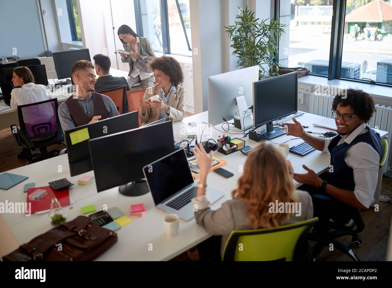 group of businesspeople in modern open space office talking, smiling ...