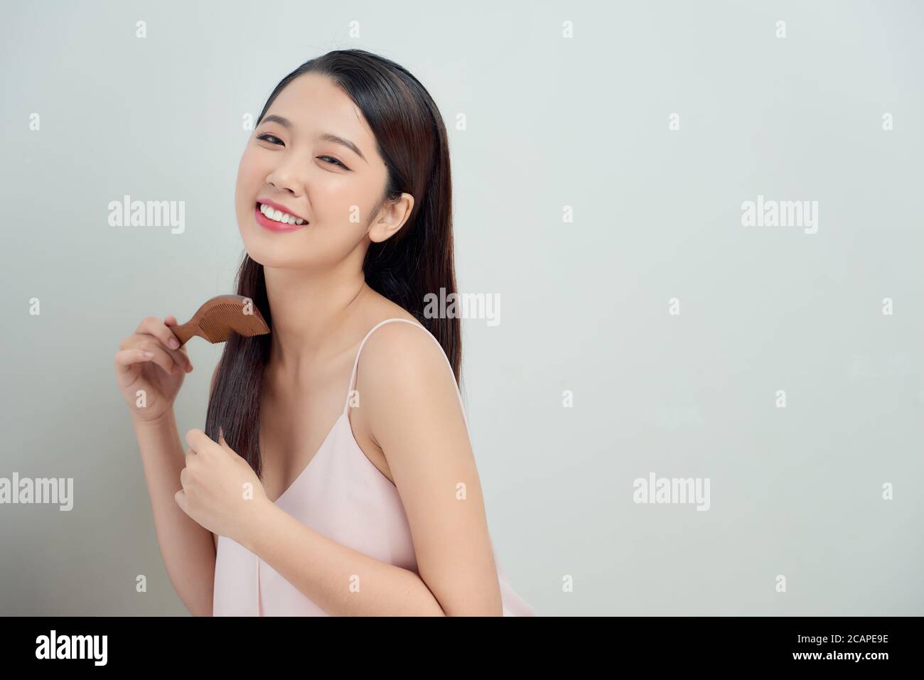 Front view of a young asian woman combing her hair isolated on white Stock Photo