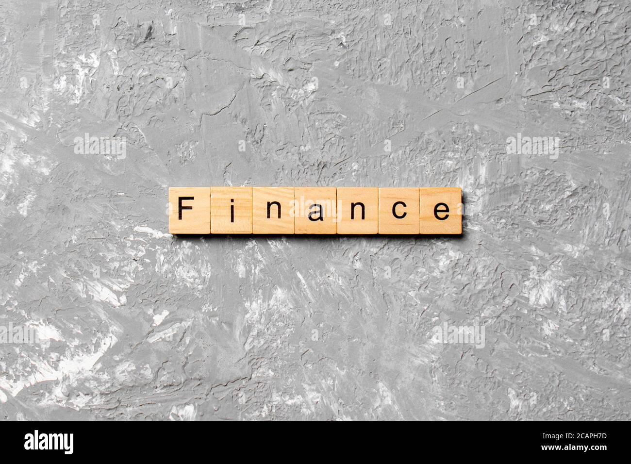 FINANCE word written on wood block. FINANCE text on cement table for ...