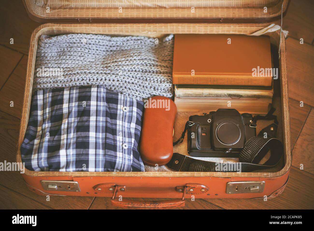 https://c8.alamy.com/comp/2CAPK85/an-open-old-orange-battered-suitcase-that-is-packed-for-the-trip-it-contains-clothing-old-books-a-case-for-glasses-and-a-rare-camera-2CAPK85.jpg