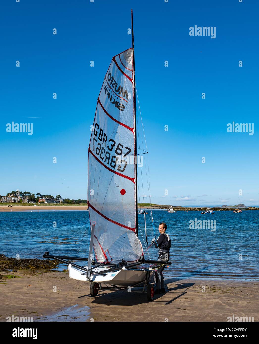 North Berwick, East Lothian, Scotland, 8th August 2020. UK Weather: Perfect day for water sports. A warm sunny day in the Firth of Forth attracts people to take to the water. East Lothian Yacht Club holds a club race as a man pulls up a sail on a Musto skiff sailing dinghy Stock Photo