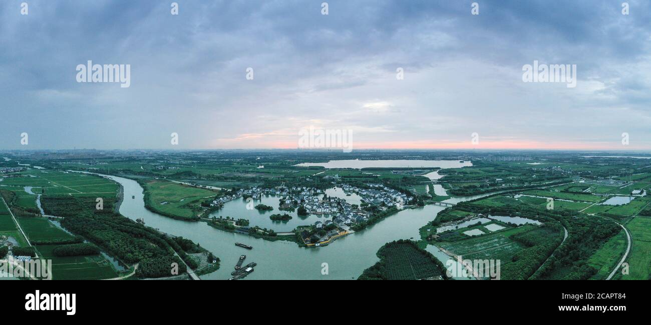 (200808) -- NANJING, Aug. 8, 2020 (Xinhua) -- Aerial panorama photo taken on Aug. 8, 2020 shows the sunrise of Jianghang Village of Zhangpu Town, in Kunshan City, east China's Jiangsu Province, . In recent years, Zhangpu Town has promoted rural construction with ecological agriculture, green agriculture and tourism agriculture as the core. The economy has continued to develop efficiently with the per capita net income of farmers reaching 46,695 yuan (about 6,701 U.S. dollars) in 2019. (Xinhua/Yang Lei) Stock Photo
