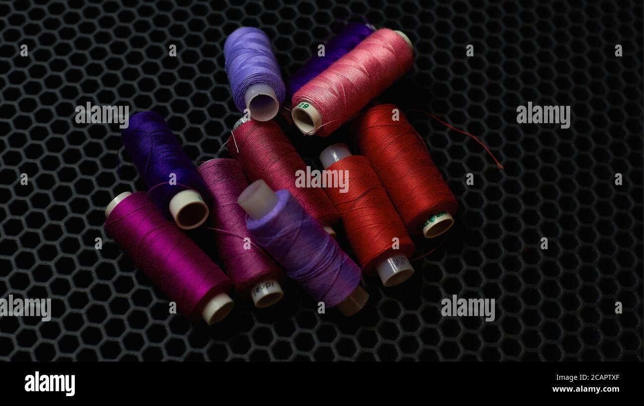 Multi-colored sewing threads on a dark background close-up from above Stock Photo