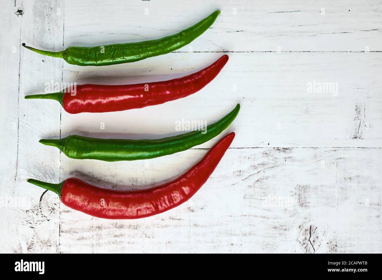 spicy green and red chilli on a light background from above close up ...
