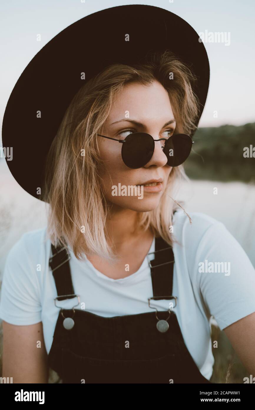 Young trendy hipster woman in black hat and dungaree Stock Photo - Alamy