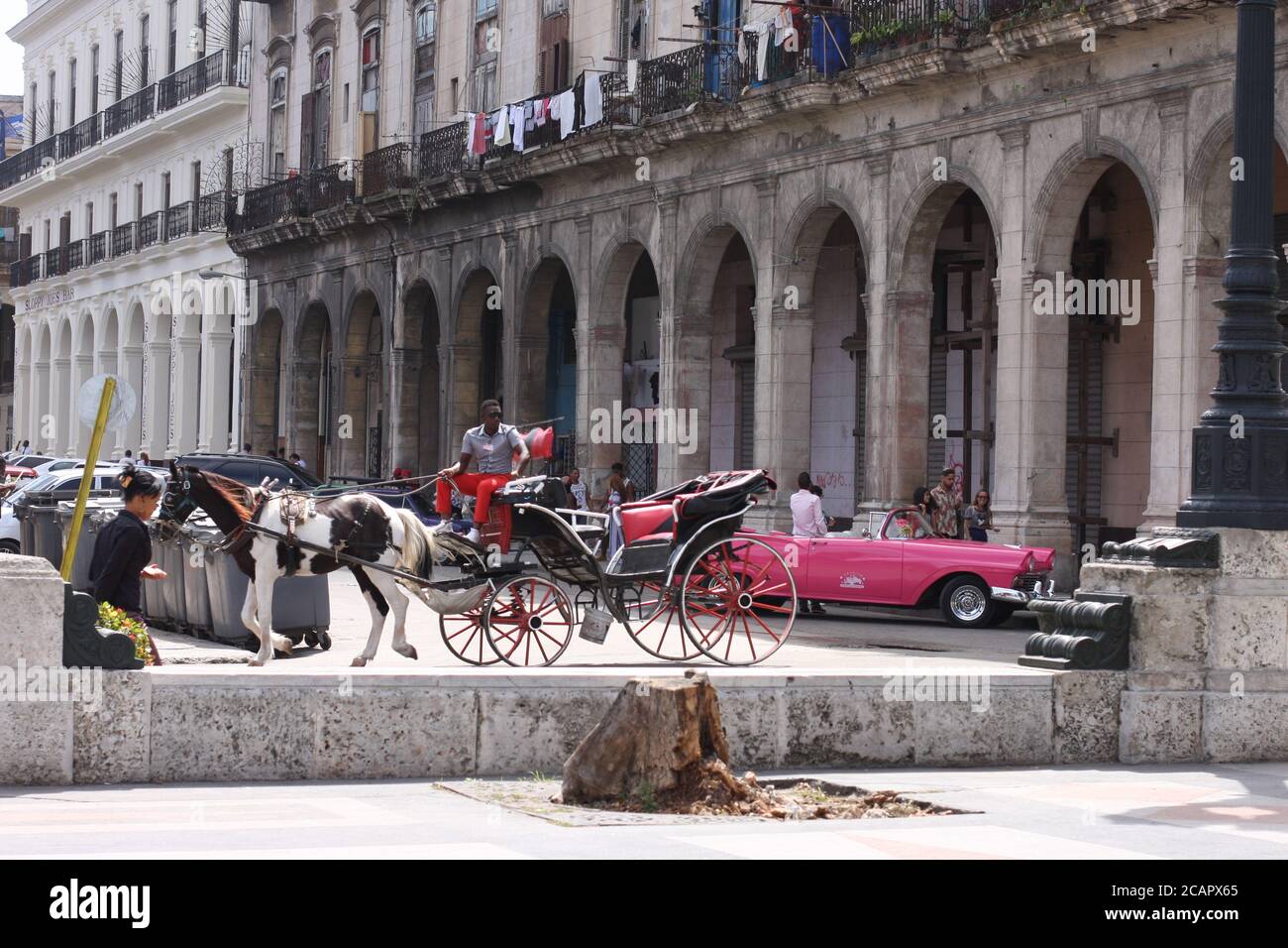 Street scene in Havana, Cuba; horse and carriage and vintage pink car Stock Photo