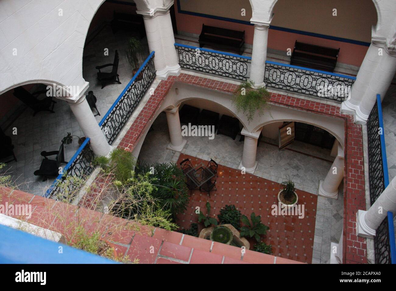 Inner open air courtyard, in colonial style, red, pink and white; Hotel Santa Isabel, Havana, Cuba Stock Photo