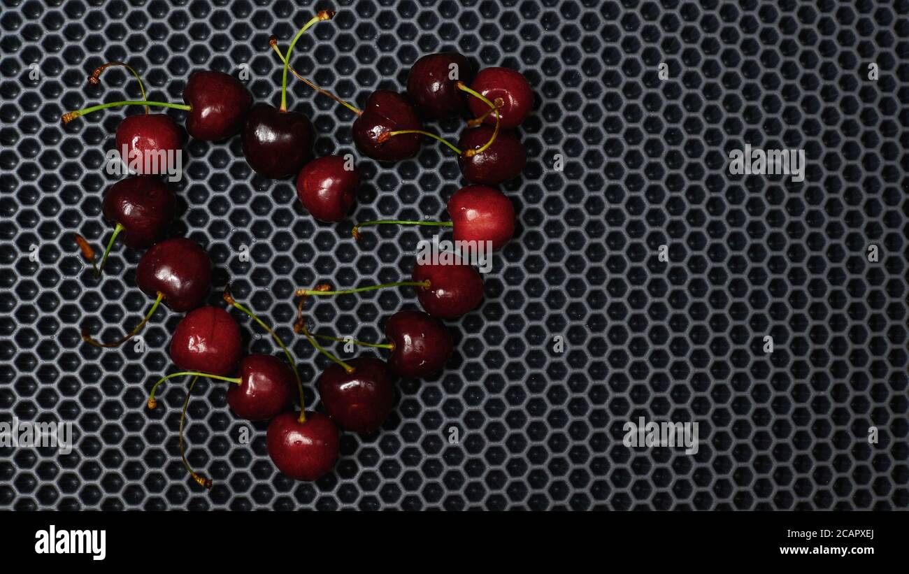 hollow heart of red cherries close up from above against a dark background Stock Photo