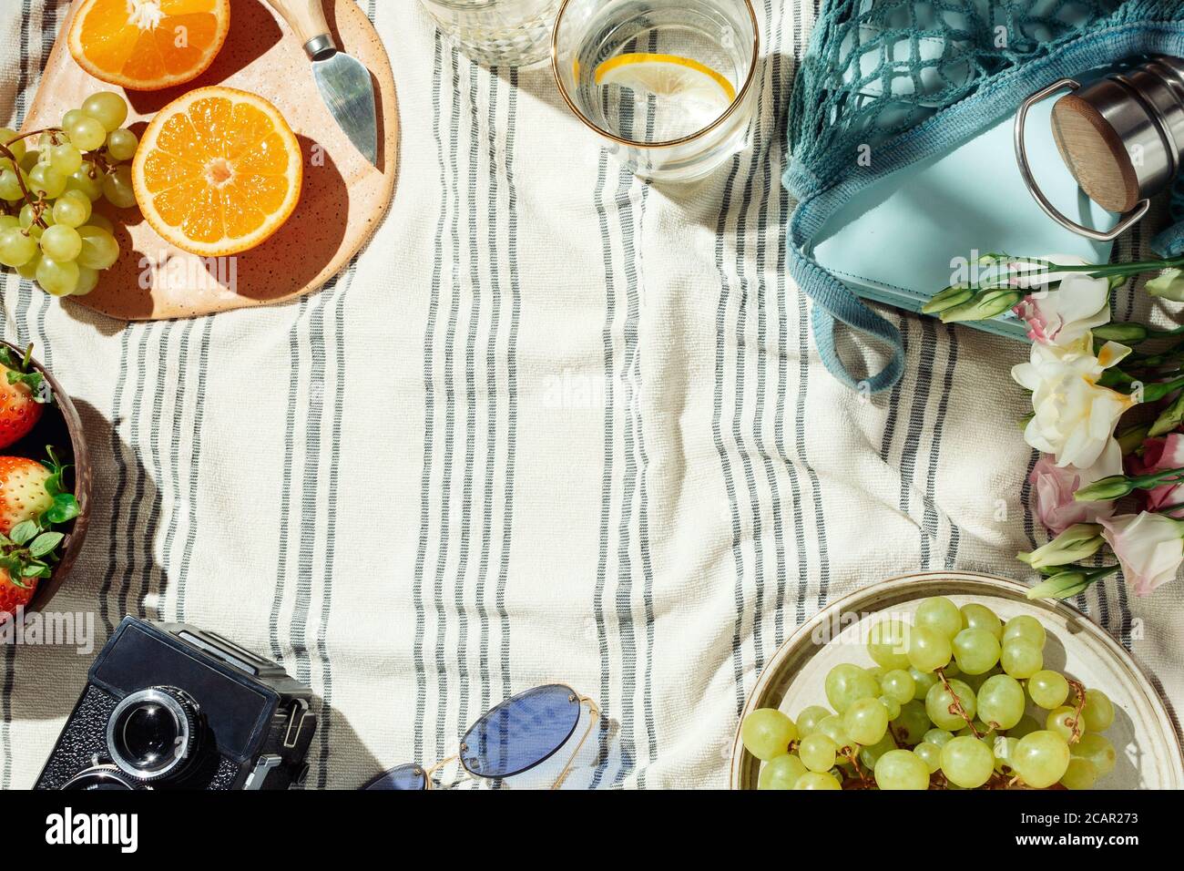 Summer picnic flatlay, fruits, berries and lemon water on striped cotton blanket Stock Photo