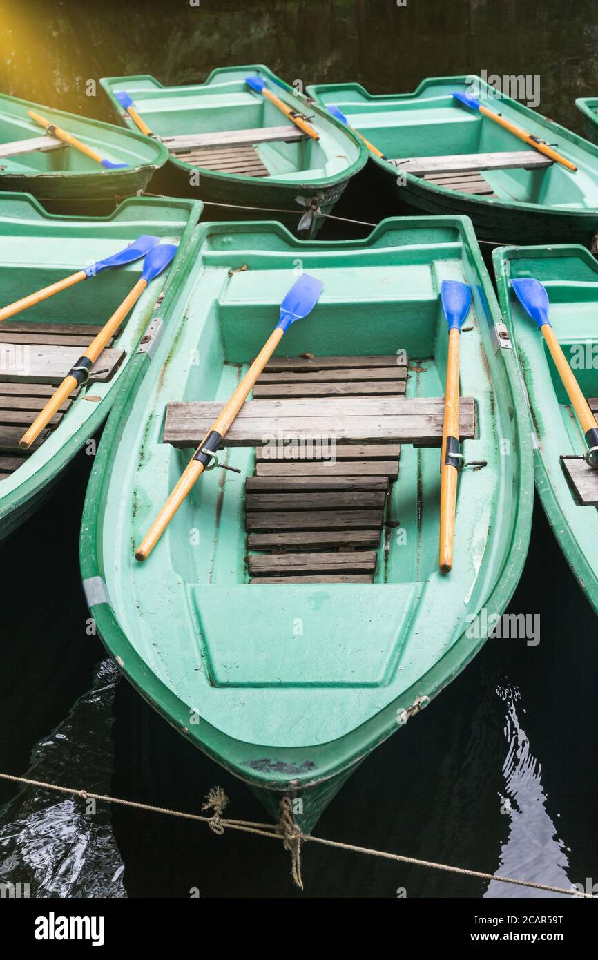 Green old empty boats with wooden oars on the lake closeup.  Recreational old row boats. Boat rental Stock Photo