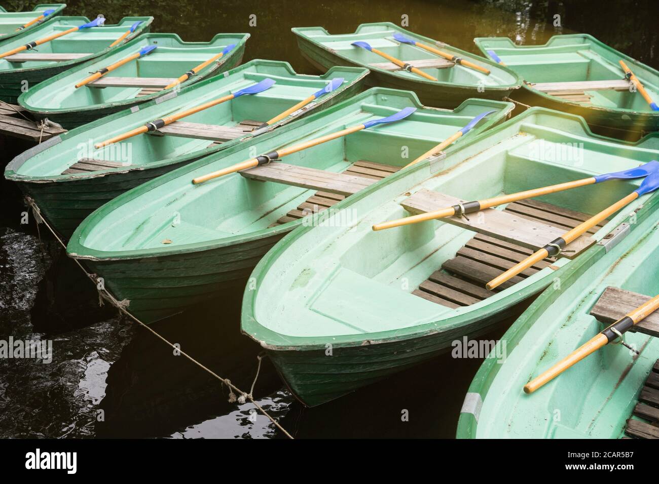 Green old empty boats with wooden oars on the lake closeup.  Recreational old row boats. Boat rental Stock Photo