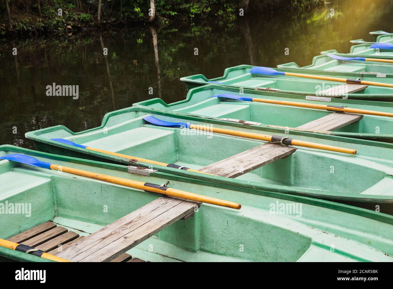 Green old empty boats with wooden oars on the lake closeup.  Recreational old row boats. Stock Photo