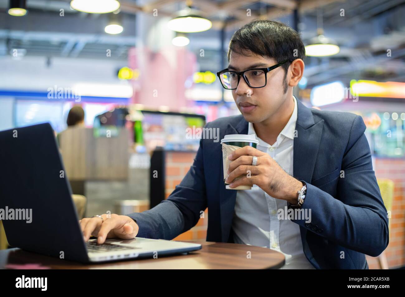 Asian businessmen are talking on the phone and drinking coffee while working Stock Photo