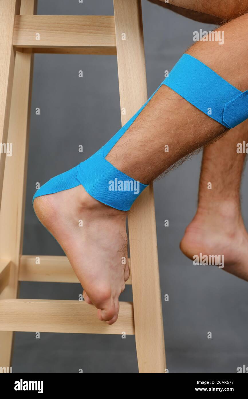 Close-up kinesiology tape applied to injured calf and heel of a white male  Stock Photo