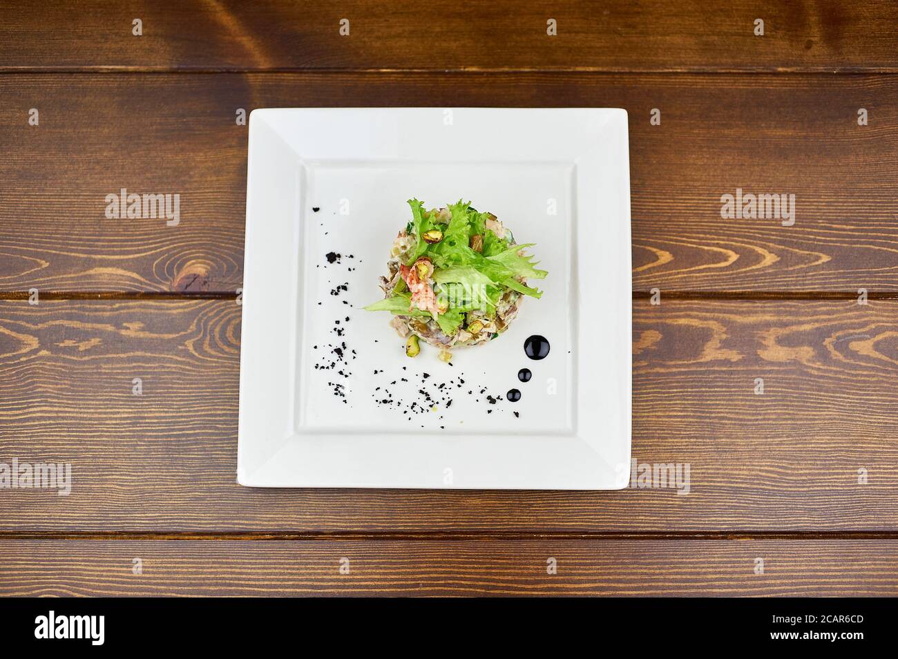 salad with crab and greens on a white plate and a wooden background Stock Photo