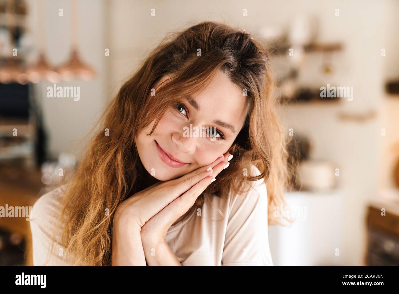 Cheerful lovely girl standing in the kitchen, looking at camera Stock Photo