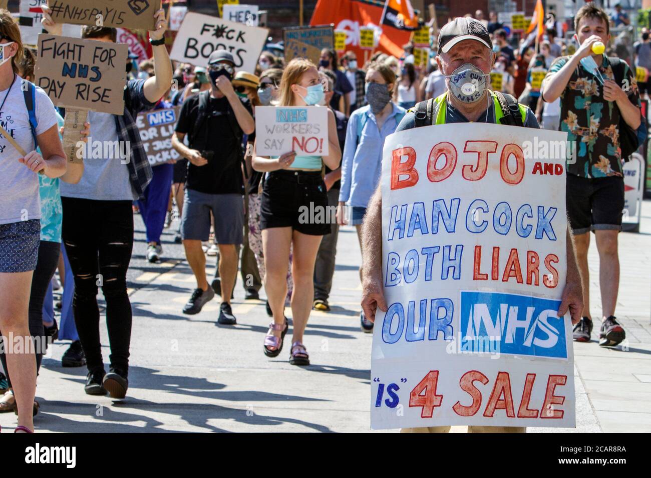 Bristol, UK. 8th August, 2020. NHS staff and members of the public are pictured as they march through Bristol to campaign for ‘pay justice’.  Thousands of NHS workers in towns and cities around the UK took part in socially distanced demonstrations in order to vent their anger that despite all their efforts during the pandemic NHS staff have been ignored and excluded from recently announced public sector pay rises. Credit: Lynchpics/Alamy Live News Stock Photo