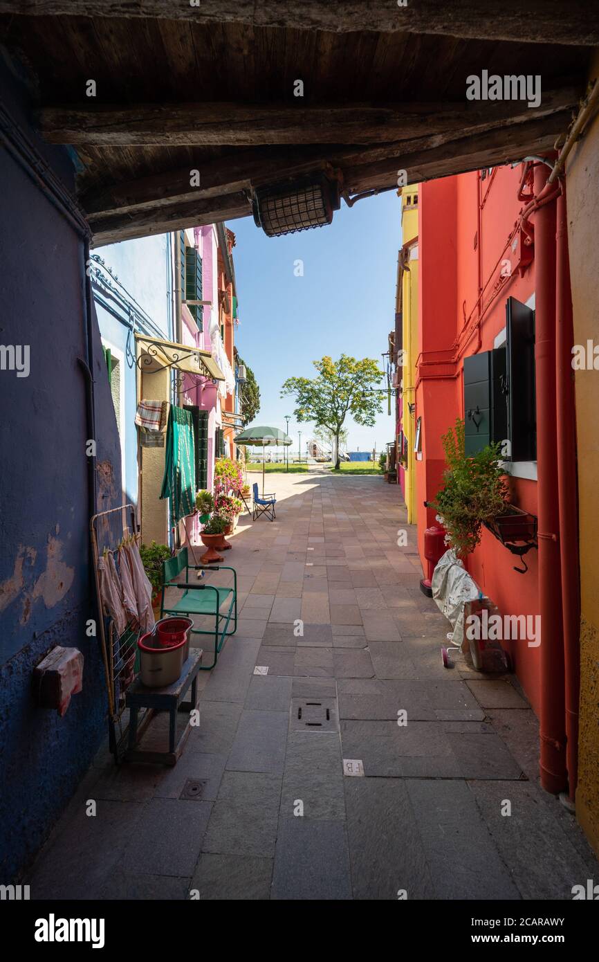 Burano island, Venetian Lagoon, Venice, Italy, a narrow passage towards the sea between the typical coloured homes in the town centre Stock Photo