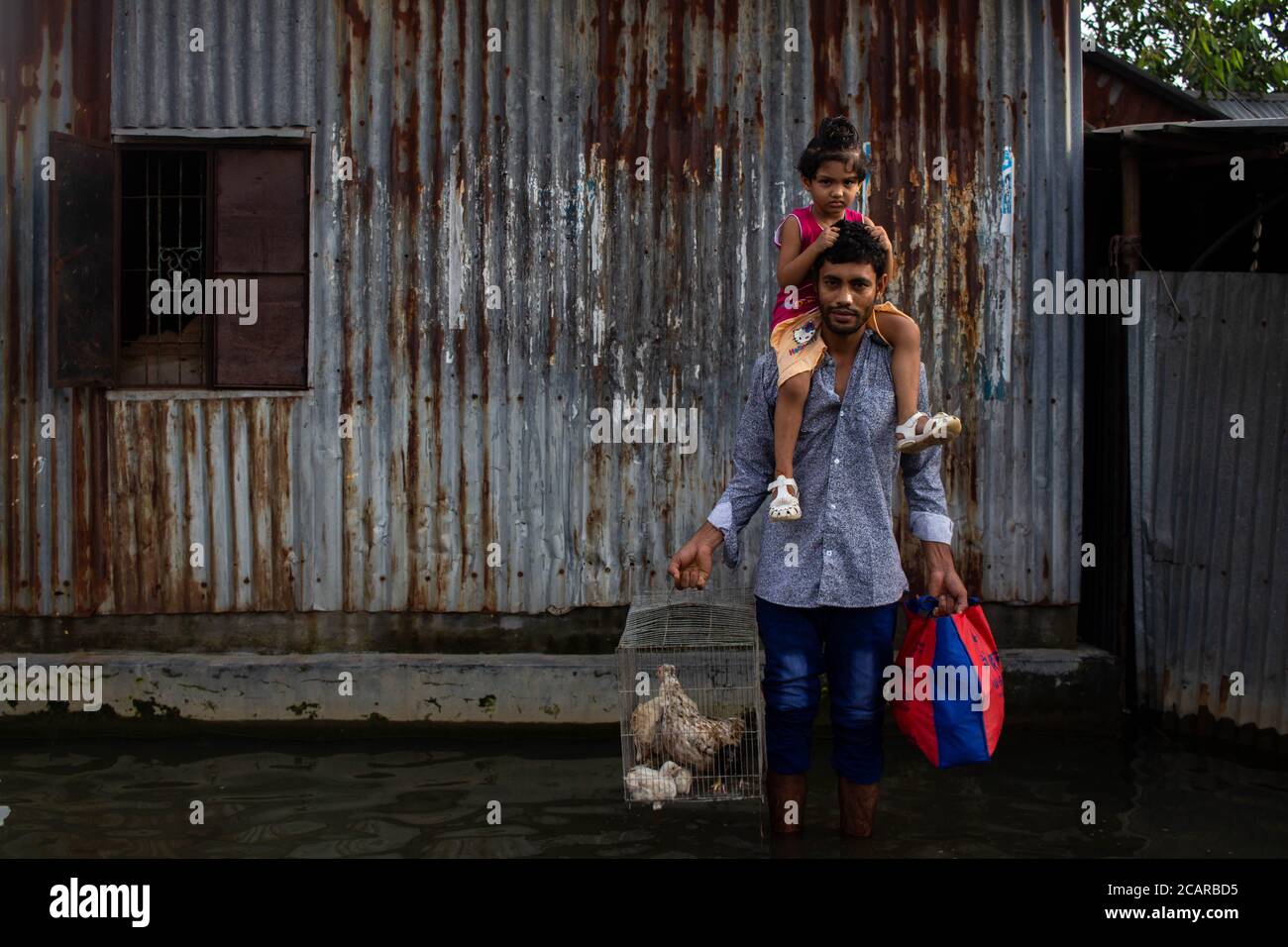 Dhaka, Dhaka, Bangladesh. 8th Aug, 2020. A man poses for a picture while carrying his child and belongings through a flooded road in Badda Rupganj, as the water of Balu River goes up. 08 August 2020. Dhaka, Bangladesh. Credit: Nayem Shaan/ZUMA Wire/Alamy Live News Stock Photo