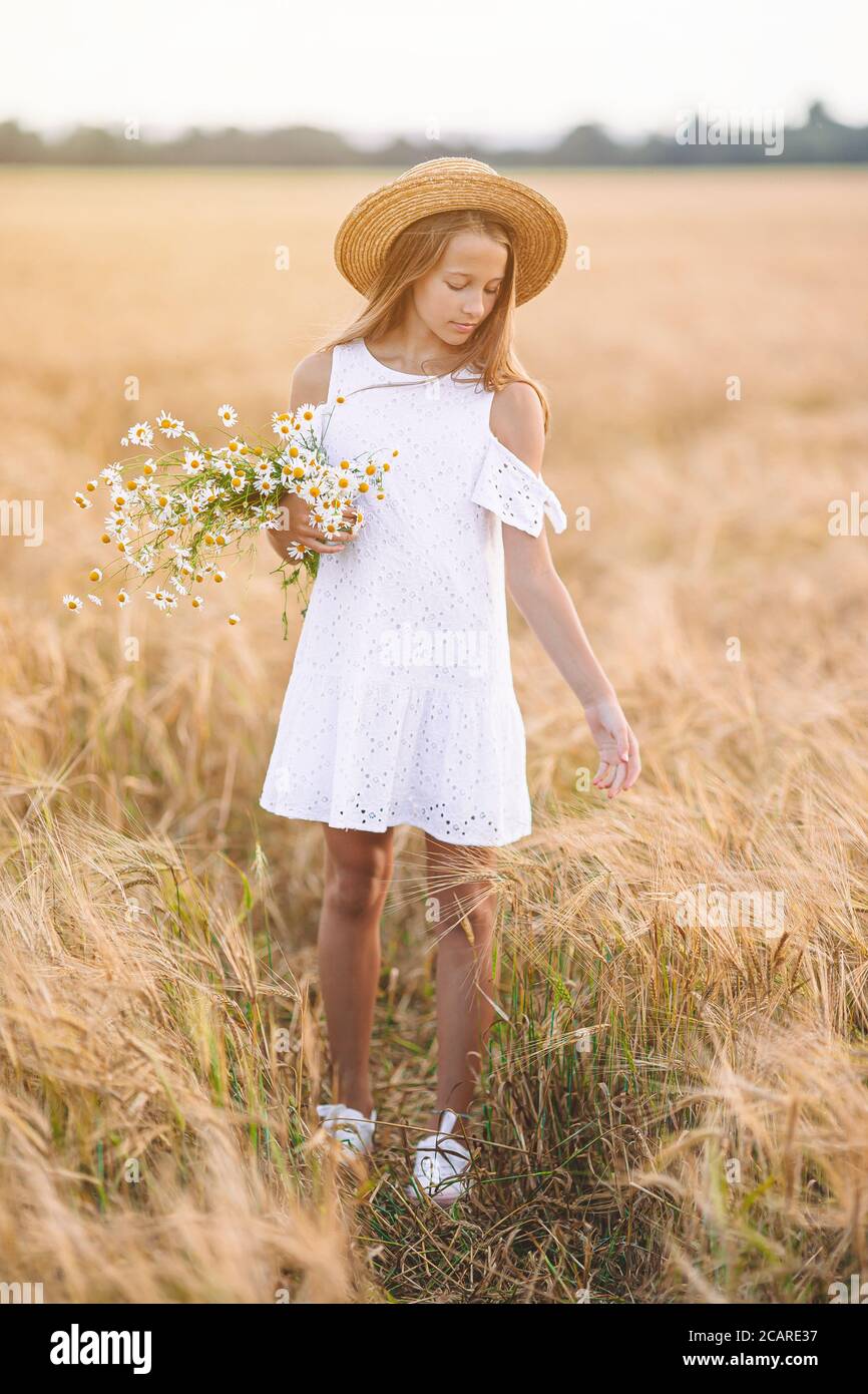 Happy child in wheat field. Beautiful girl in white dress in a straw ...