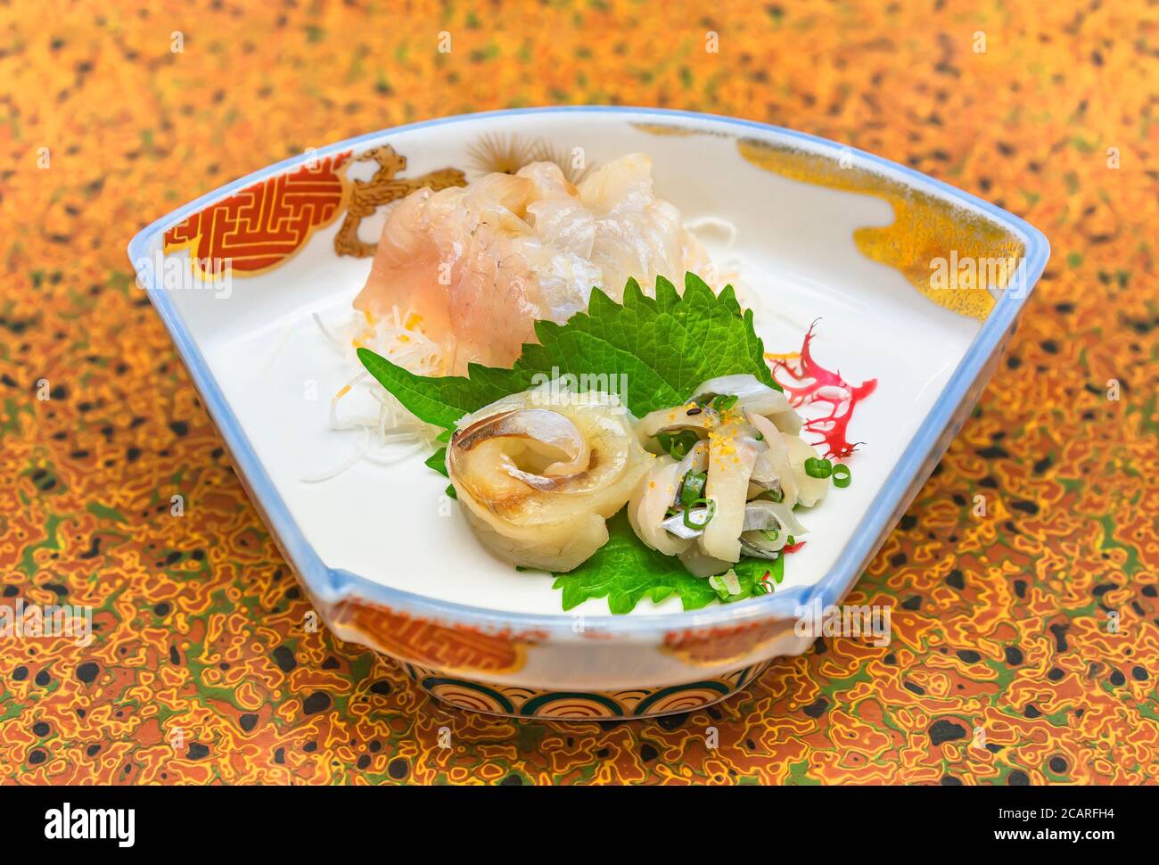 Raw sashimi high-class japanese cuisine of fresh Sayori needlefish, Madai seabream and Hirame halibut in a dish plate with Gracilaria red algae Stock Photo