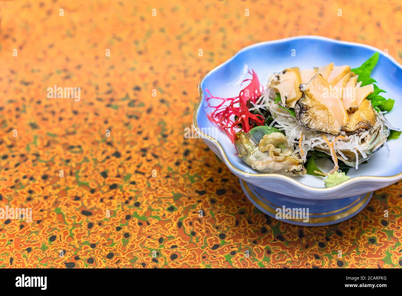 Raw sashimi high-class japanese cuisine of fresh Awabi abalone in a dish plate with Gracilaria red algae, shiso leaves and julienne of daikon radish a Stock Photo