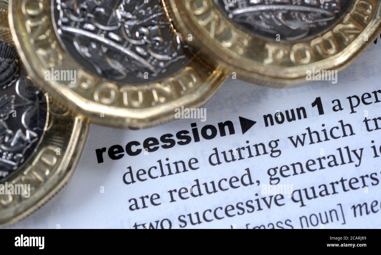 BRITISH ONE POUND COINS WITH DICTIONARY DEFINITION OF WORD RECESSION RE THE ECONOMY CORONAVIRUS COVID-19 PANDEMIC GLOBAL ETC UK Stock Photo