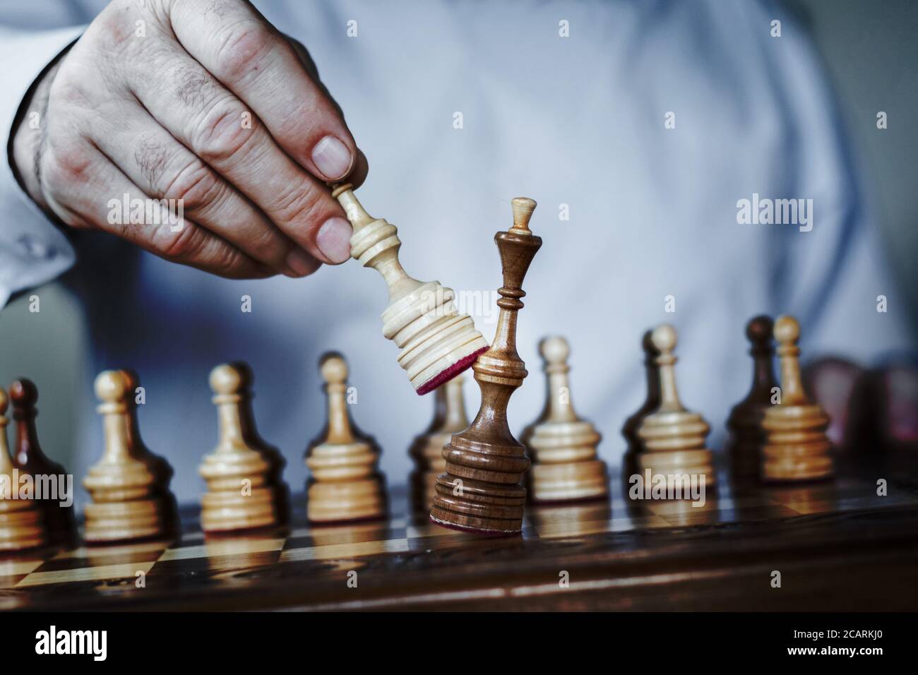 Close up of hands of a business man moving king golden chess to defeat  opponent the chess game is development analysis, strategy, and plan, the  management or leadership concept. 22804709 Stock Photo