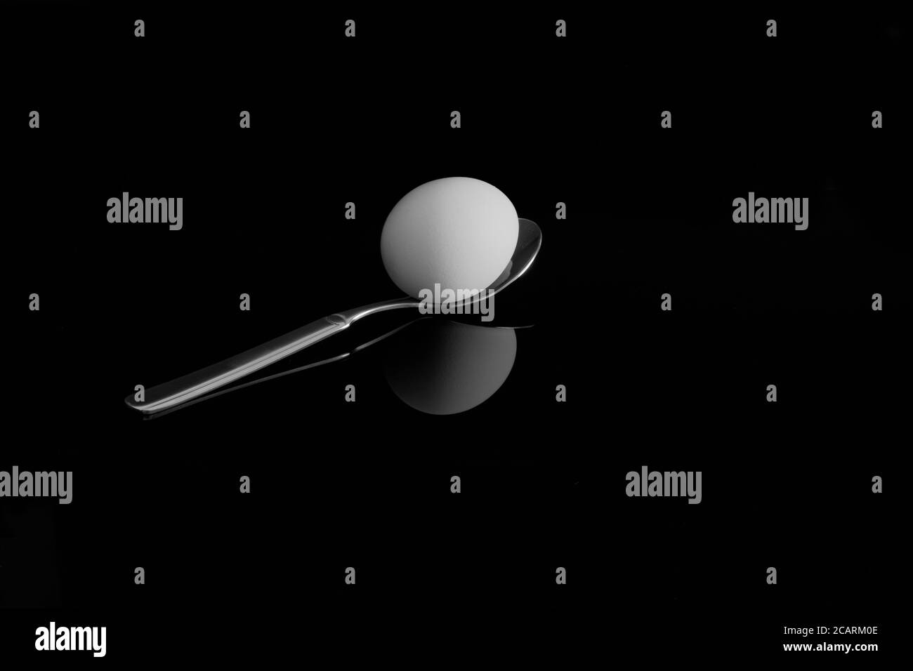 An egg on a spoon. With reflection on a black background Stock Photo